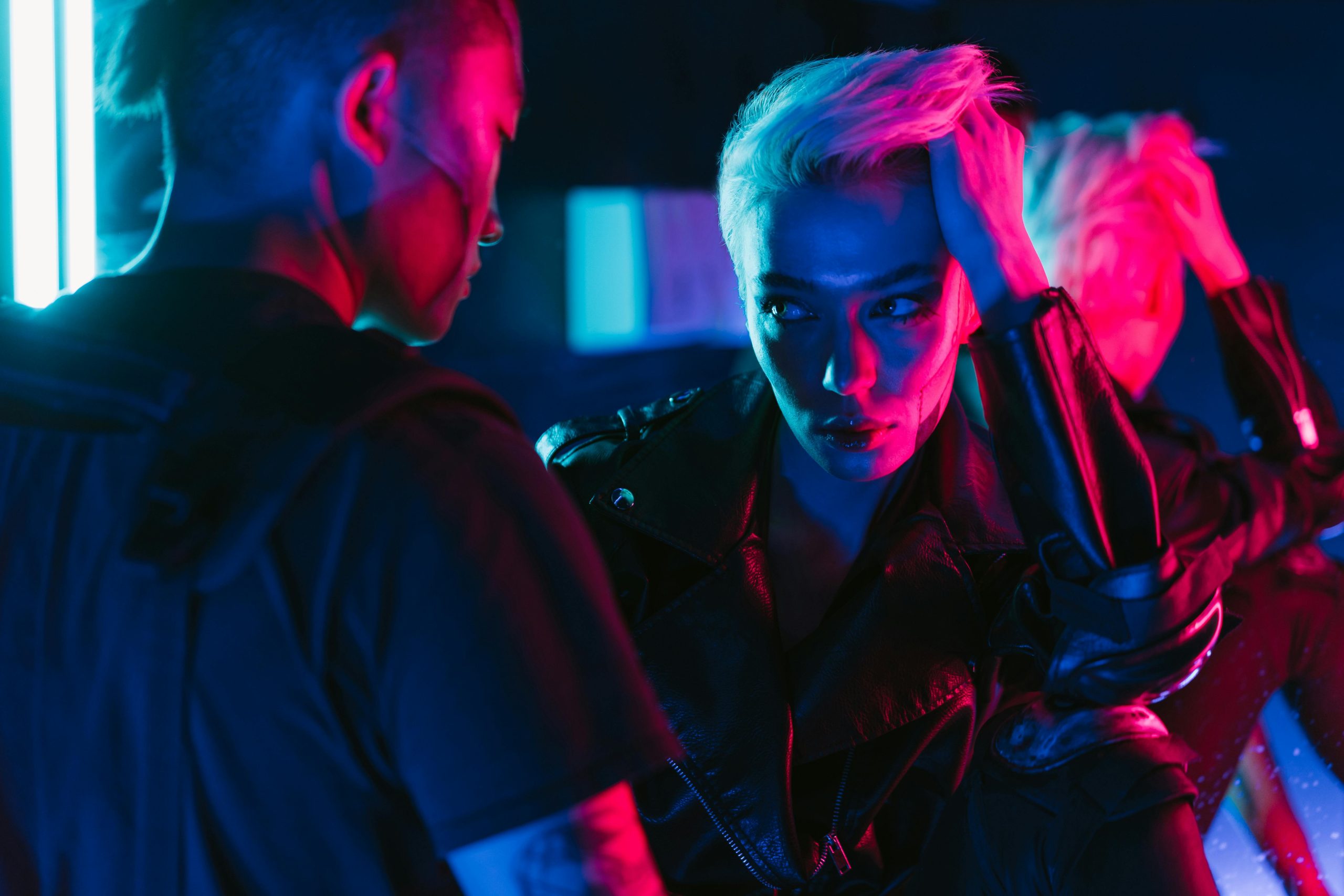 Stylish individuals in neon lights embodying cyberpunk fashion and futuristic vibes.