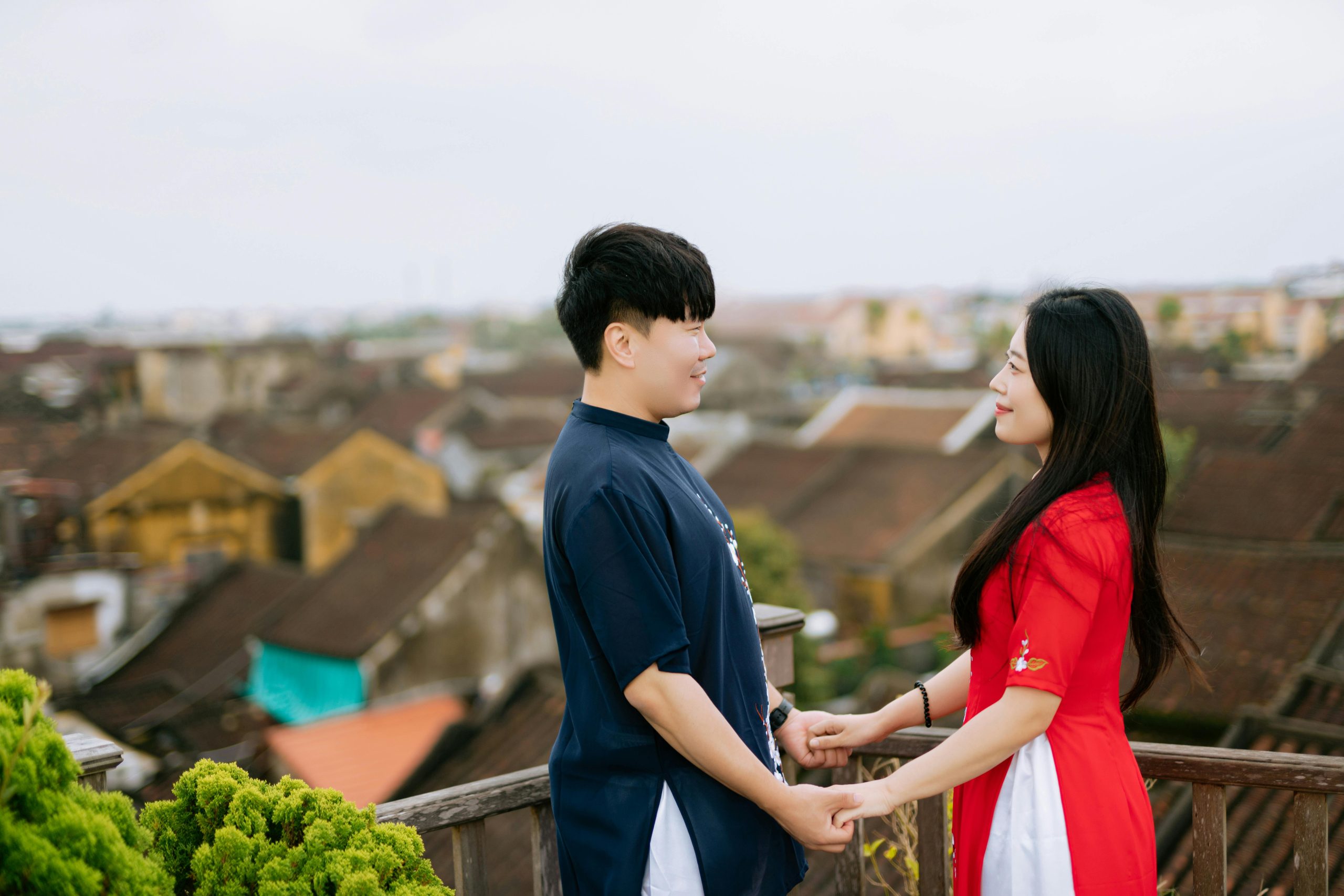 Romantic Asian couple enjoying a moment together, holding hands with a scenic outdoor backdrop.