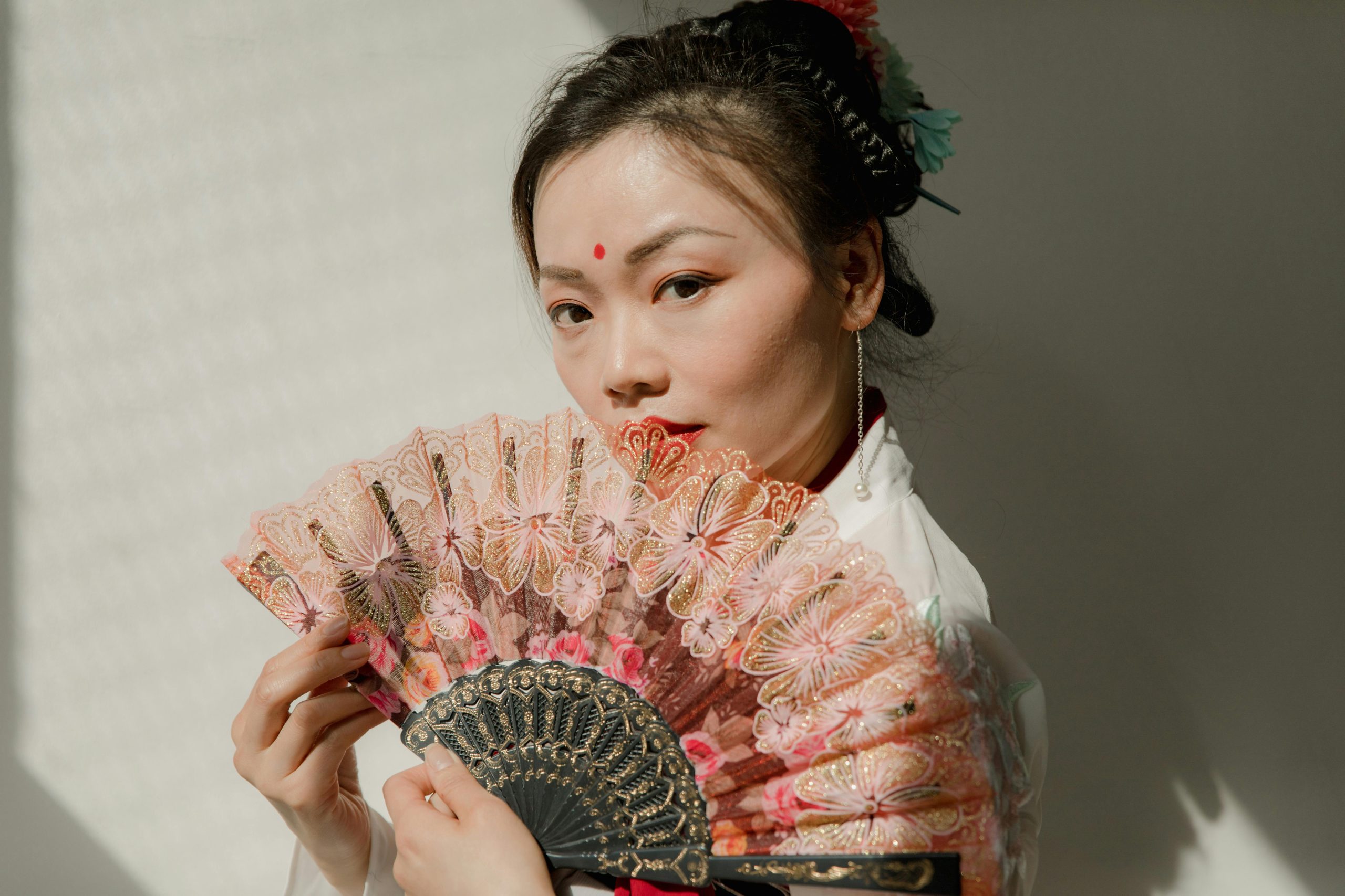 Portrait of an adult woman with traditional clothing and hand fan. Captivating and elegant pose.
