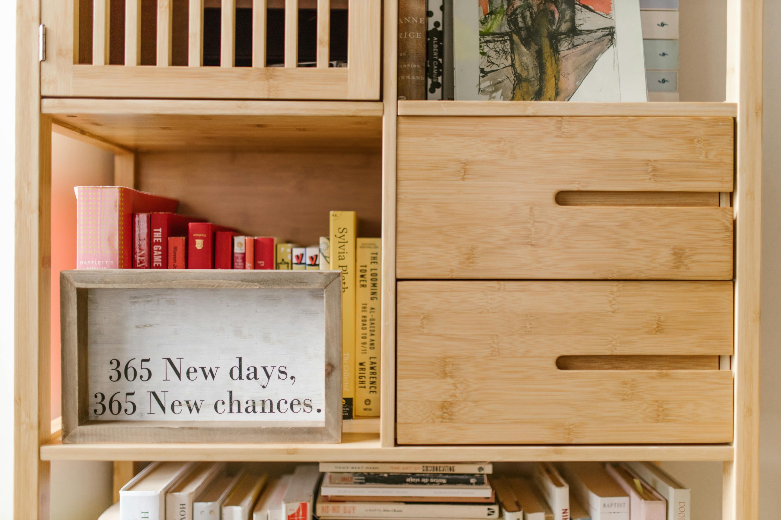 Wooden bookshelf with books and a motivational quote sign: