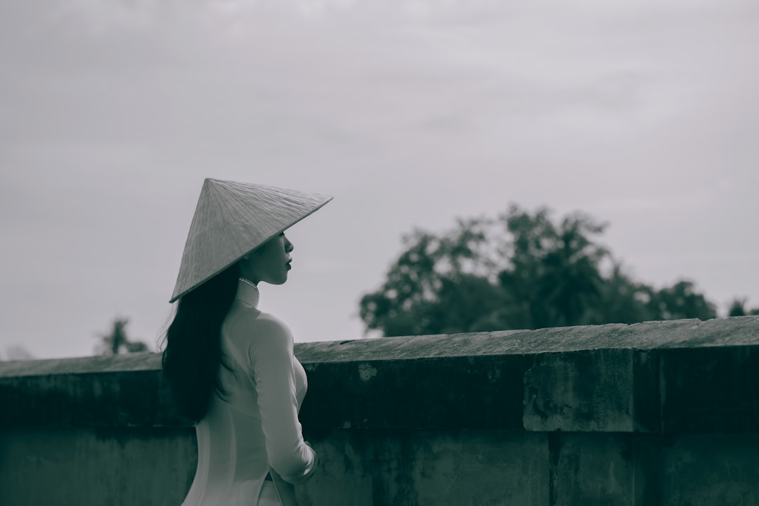 a woman wearing a hat standing next to a wall
