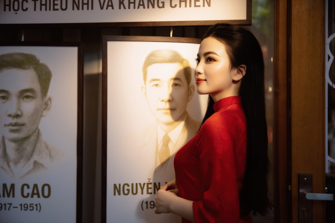 Woman in red dress posing next to historical portraits